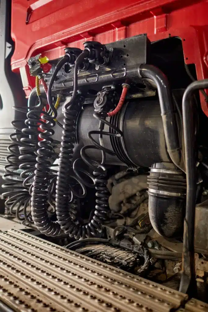 Flexibles d'Air et Connecteurs Électriques de Camion Flexibles d'air comprimé et câbles électriques en spirale à l'arrière d'une cabine de camion rouge.